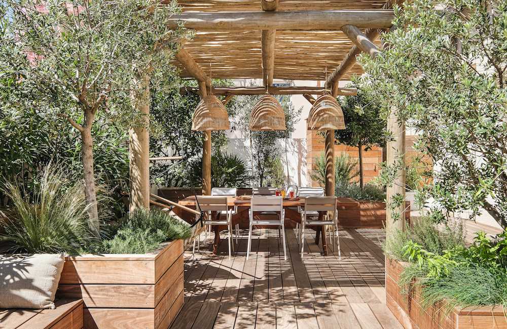 Pergola en bois naturel sur terrasse avec végétation méditerranéenne, espace ombragé et convivial dans un jardin du Var